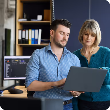 2 NieuweStroom-collega's, 1 houdt een laptop vast, de ander wijst naar het scherm.