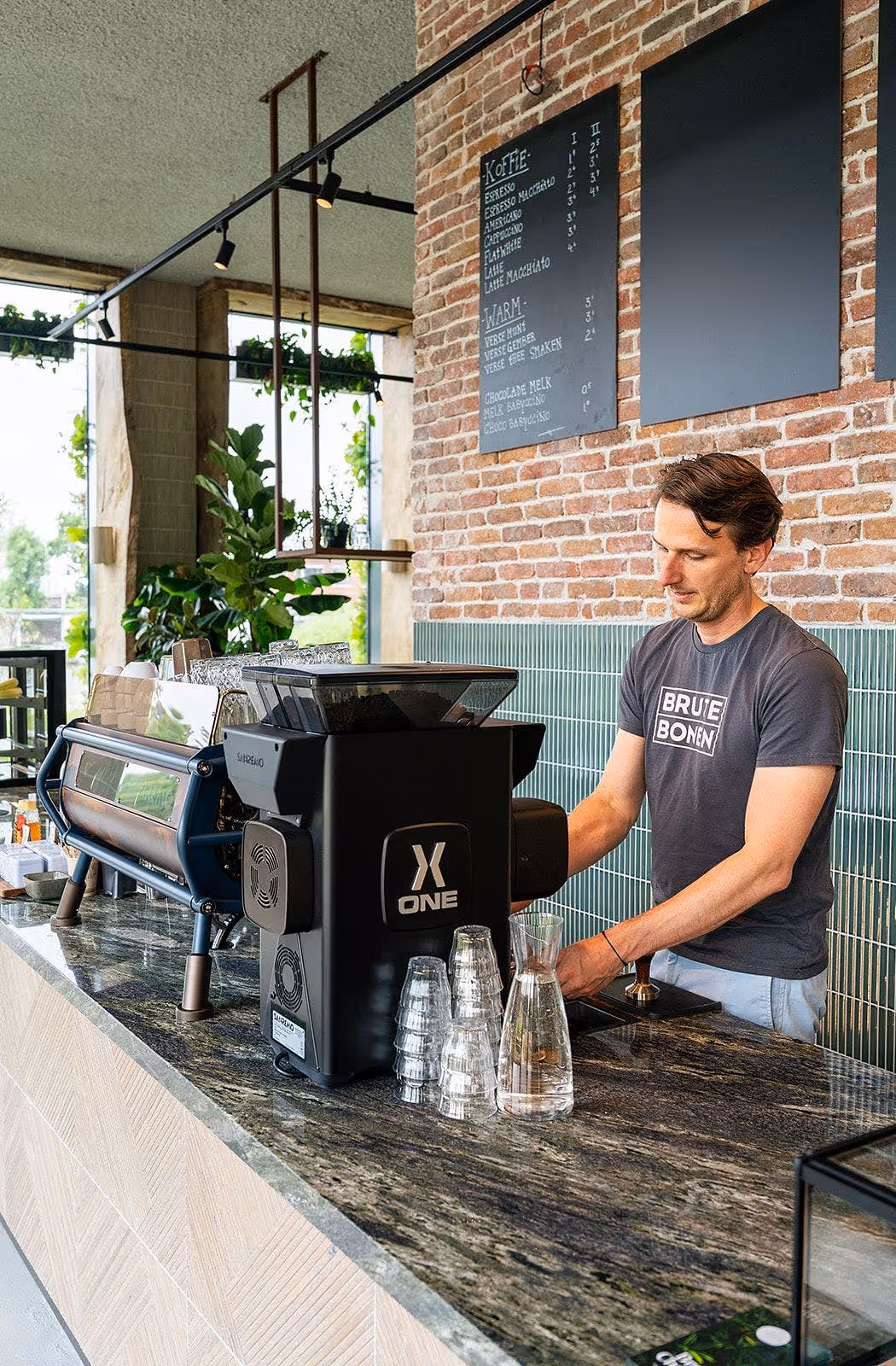 Barman achter een espressomachine in een koffiezaak.
